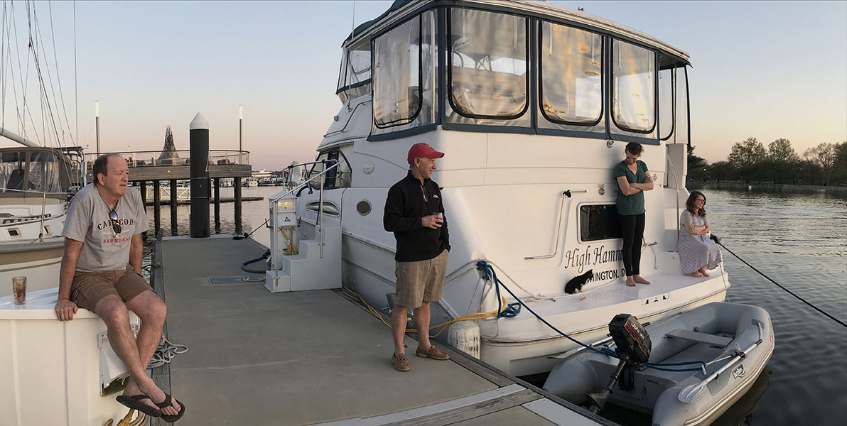 People on Dock in Front of Boat Drinking and Watching.
